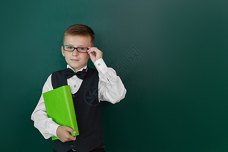 带着领结和眼镜的可爱聪明男孩手握着一本书 第一次上学 回到学校里去孩子女性手指乐趣男生喜悦瞳孔教育黑板幼儿园图片