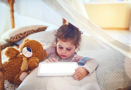 现在的孩子们很快就能掌握技术 一个可爱的小女孩在家里使用数字平板电脑图片