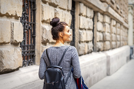 年轻妇女背着背包走路夹克黑发女性旅行教育青少年街道学校游客闲暇图片