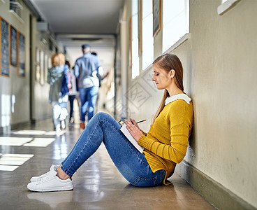 她利用一切机会学习 一位在大学走廊学习的迷人年轻女学生的全长镜头图片