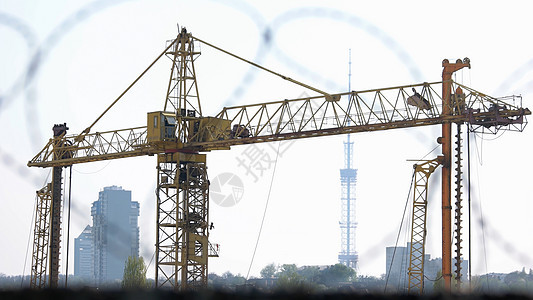 黄色建筑起重机在城市背景上图片