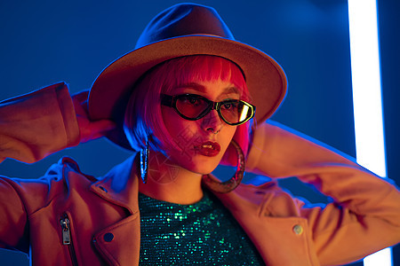 在发光的霓虹灯下派对上迷人女人的画像 夜总会 时髦的衣服 少年 Zoomer Z 世代 戴着帽子和眼镜的女士舞蹈女性展示广告爆炸图片