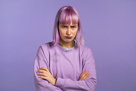 愤怒的冒犯女人 头发染成紫色 双臂交叉 用怀疑的眼神盯着镜头 对某人感到生气 人的面部表情 情绪和感觉 身体语言图片