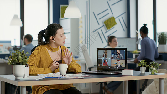 在与客户和经理举行电视会议时使用膝上型电脑的开办办公室雇员 他们谈论营销图片