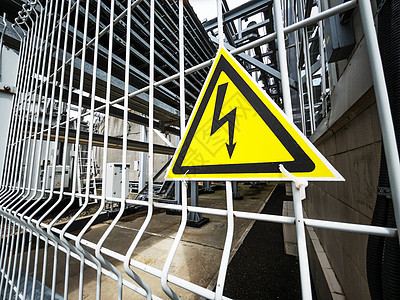 危险信号 在金属网格上的黄色三角形的高压电压电缆死亡栅栏技术警报闪电注意力变压器警告力量图片