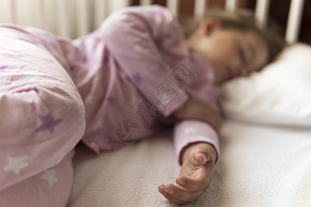 可爱开朗的小 34 岁学龄前女婴在午餐休息时间穿着粉红色睡衣和枕头在家里甜蜜地睡在白色婴儿床上 童年 休闲 舒适 医药 健康理念图片