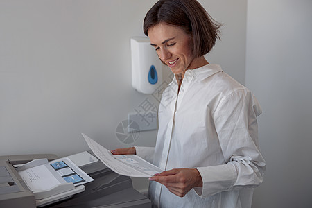 在现代办公室内 在复印机上扫描文件的女工人笑脸屏幕电脑人士秘书控制板传真女士管理人员打印女孩图片