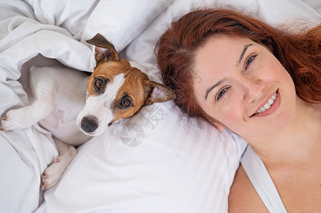 狗和房主躺在床上女性宠物友谊毯子快乐假期女士长椅微笑卧室图片