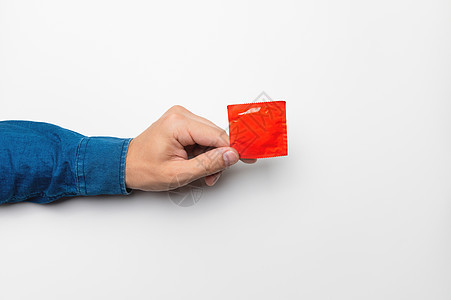 男人的手在白色背景的包里拿着一个红色避孕套 高定义产品 近距离接近 避孕图片