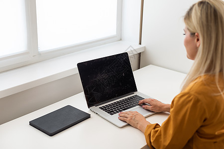 年轻美丽的快乐女人在办公室用笔记本电脑工作时微笑的画面学习房间员工女孩们职场设计师黑发软件金发女郎网站图片