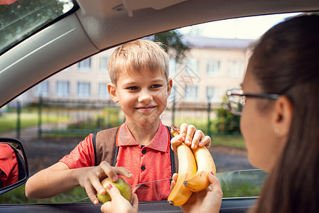 母亲用车窗向她笑着的儿子赠送水果图片