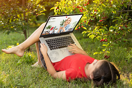 美丽的小姐姐在户外和朋友聊天 置身于大自然中很有用 笔记本电脑是当今孩子最好的朋友 绿色广阔的草地金发花园微笑互联网季节乐趣技术图片