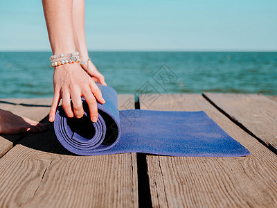 年轻漂亮的运动女青年准备在水边海滩上做瑜伽 女孩覆盖紫色垫子 健康概念姿势女性日落冥想训练海洋身体精神女士生活图片