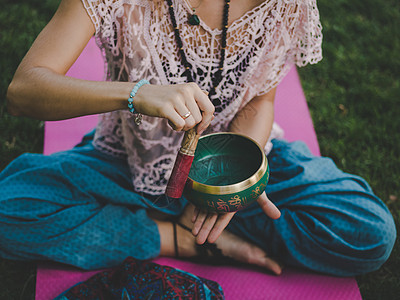 夏天 女人坐在绿色公园的瑜伽垫上玩唱歌碗 复古色调 美丽的女孩与 mala 珠子在绿草上打坐康复治愈者树木医疗保健瑜伽头发冥想乐图片