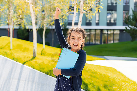 小美丽微笑的女孩拿着书 去上学 特写肖像 童年 孩子抱着一本书 生活方式 兴趣 爱好 空闲时间 空闲时间青年太阳快乐铅笔背包教育图片