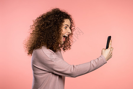 愤怒的咖喱女人大喊大叫 跟某人发誓 用手机 粉红背景的压抑和沮丧的女孩们图片