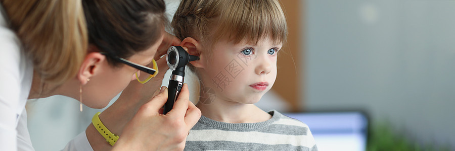 女儿科医生在诊所使用眼透镜观察小女孩的耳朵图片