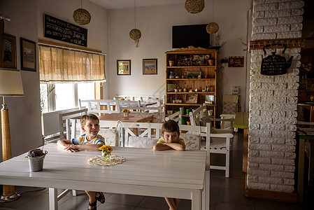 现代室内咖啡店风格 生态环境以及墙上的植物 咖啡店 两个儿童坐在桌旁的长椅上 等待美食木头生物标签桌子奢华食物装饰质量咖啡厨房图片