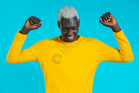 蓝工作室背景的非洲男子舞跳得积极 黄色的男性黑人模特男 派对 快乐 自由 青年概念 笑声潮人音乐漫画俱乐部舞蹈黑发优美头发爆炸魅图片