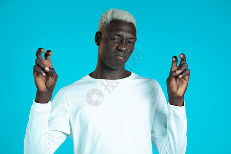 留着白发的非洲男人用手和两个手指像引号手势一样展示 弯曲的手指被蓝色背景隔离 非常有趣 讽刺和讽刺的概念图片