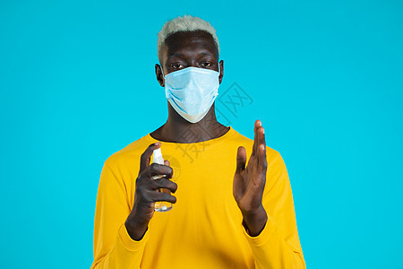戴防护面具的非洲男子在手上涂上消毒剂 然后展示 — 它是干净和无菌的 停止病毒概念 细菌保护图片
