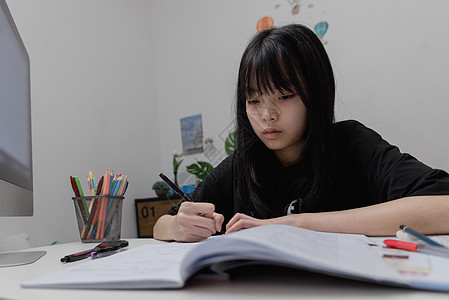 亚裔女学生在书桌上写家庭作业和阅读书青少年学习大学女孩学校瞳孔女性绘画教育童年图片