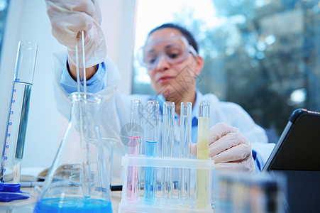 关注测试管 在实验室助理助理液态吸液物质的模糊背景上进行化学反应;以试验管为重点图片