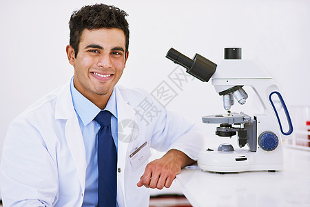 一个微笑的实验室技师 坐在实验室里时用显微镜画作的肖像 他就是这么认为的图片
