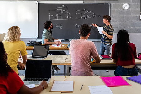 男高中生在多种族同学面前做口语班讲课 教师作笔记 您可前往学校听音乐 请访问InfoFinland上的芬兰语和瑞典语图片