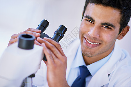 一个微笑的实验室技师 坐在实验室里时用显微镜画的肖像 他就是这么看的图片