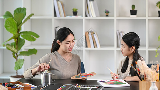 年轻的亚洲教师在绘画课上画画时 照顾孩子的年青老师图片