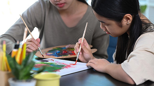 年轻女教师帮助小女孩在艺术课上画画 (笑声)图片