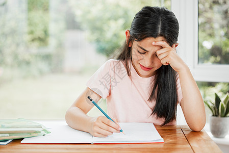 压力大 沮丧和不开心的女孩独自在家写作业 任务艰巨 疲惫的小学生正在为一场艰苦的考试而学习 通过在家上学教育扰乱学生的学习图片