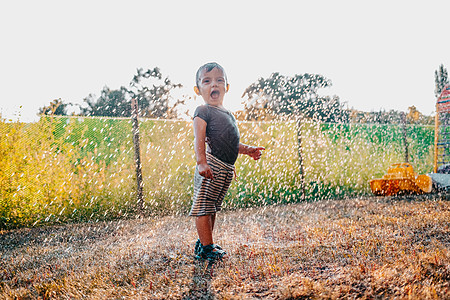 可爱的小孩在雨下玩得开心 宝贝笑了 他天气真好童年男婴气候喜悦街道季节男生乐趣快乐微笑图片