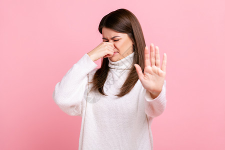 女人拿着鼻子 恶心地尖刻着脸色 露出停止的手势 表示厌恶到发臭图片