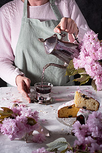 一位女性从银茶壶里倒茶 粉红樱花背景玻璃花朵休闲香气女士饮料活动热饮桌子杯子图片