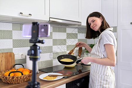 年幼女孩 食物博客在厨房做煎煎饼与橙子煮饭火炉渠道相机视频平底锅早餐拍摄互联网烹饪博主图片