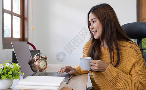 智能中国女孩Ceo专家坐在桌边工作 远程笔记本电脑文字打字报告的侧面相片 在室内装着饮料杯女性工人企业家会议杯子微笑自由职业者咖图片