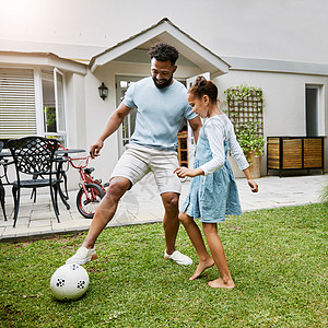 父亲和女儿亲密无间 在家里的后院踢足球 微笑着玩得开心 快乐的父母正在嬉戏 享受与孩子的家庭时光 男人对他的孩子很活跃图片