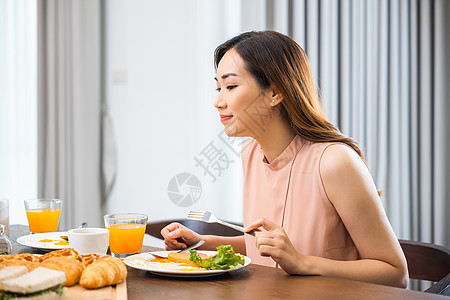 坐在厨房餐桌旁的亚洲年轻女性在家吃健康早餐图片