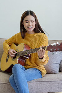 在沙发上弹吉他的女人 在家里开心地弹吉他图片