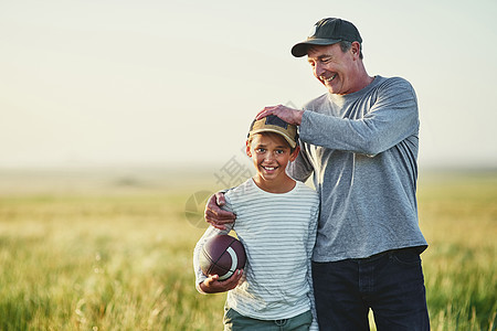 父亲和儿子在田地上玩橄榄球 爸爸教了我所有我需要知道的足球知识图片