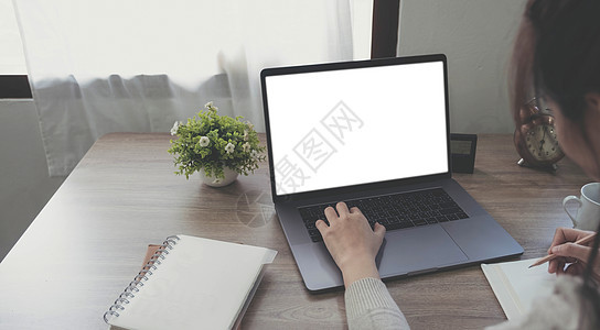 一个女人在笔记本电脑上使用和打字的模型图像 木桌上有空白的白色桌面屏幕成人女士工作商务肩膀互联网店铺办公室桌子键盘图片
