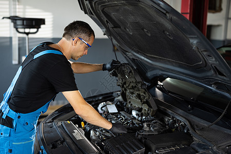 汽车修理工在修理车库的敞篷发动机时注意修理零件 机械师打开汽车引擎盖并检查发动机 汽车发动机过热 开盖电机图片