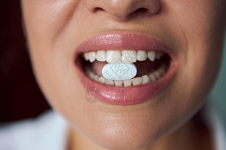 白药片 在模糊的孕妇嘴里配有饮食补充剂 微笑着美丽的牙齿笑容图片