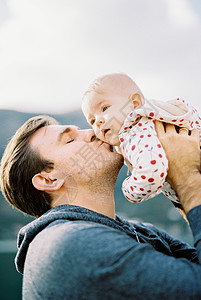 爸爸把婴儿抬高头顶 亲吻他的脸颊 肖像图片