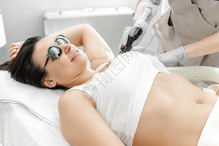 一个女孩在手术和微笑期间躺在激光除发上 并微笑着图片