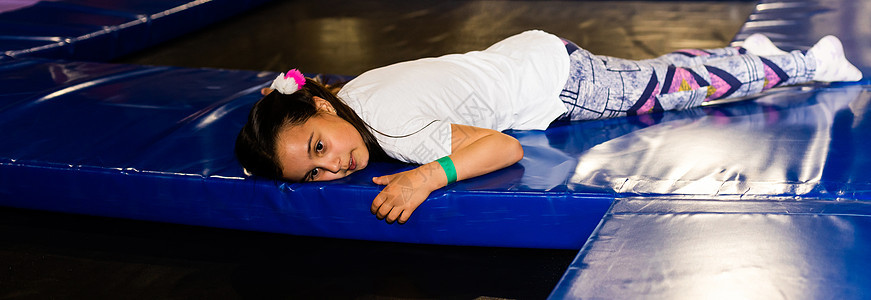 小可爱的笑笑女孩 躺在蹦床上锻炼假期头发活动孩子操场娱乐女士快乐游戏图片