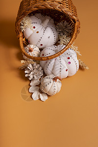 白色装饰手在彩色背景的篮子里用闪亮的石头和松果做南瓜 感恩节概念背景