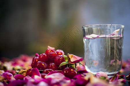 由一些与水充分混合的甜樱桃组成的黑色表面上自然发光皮肤的面膜 拍摄新鲜樱桃 一杯水和一些展开的玫瑰花瓣化妆品护理治愈卫生头发温泉图片